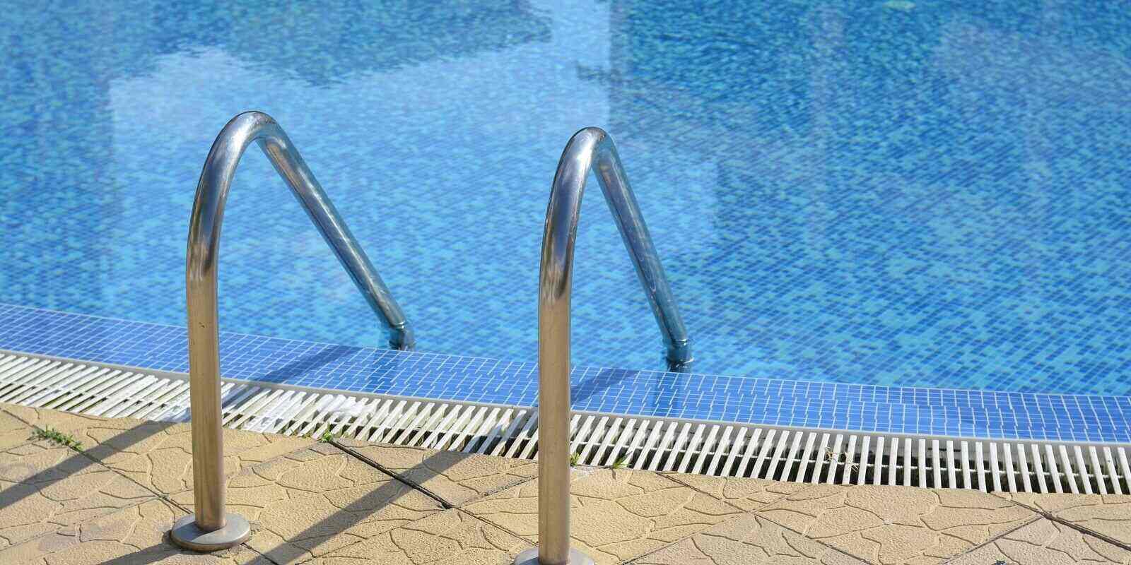 swimming pool with ladder and handrails on sunny day